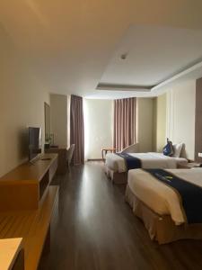 um quarto de hotel com duas camas e uma televisão em Khách sạn Sài Gòn Vĩnh Long em Vĩnh Long