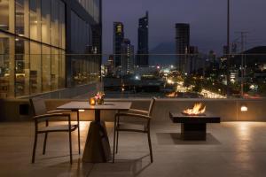 einen Tisch und Stühle auf dem Balkon mit Blick auf die Skyline der Stadt in der Unterkunft Hyatt Place Monterrey Valle in Monterrey