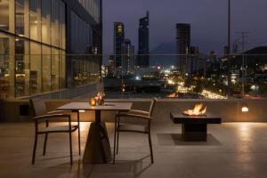 a table and chairs on a balcony with a city skyline at Hyatt Place Monterrey Valle in Monterrey