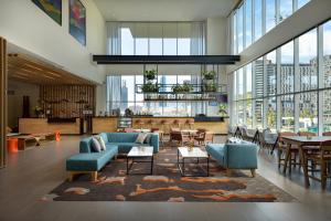 - un hall avec des canapés bleus, des tables et des fenêtres dans l'établissement Hyatt Place Monterrey Valle, à Monterrey