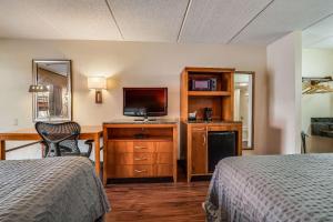 a hotel room with two beds and a desk with a television at Econo Lodge Inn & Suites in Griffin