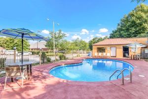 a swimming pool with a table and an umbrella at Econo Lodge Inn & Suites in Griffin