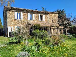 una antigua casa de piedra con un jardín delante de ella en Les Romarins B&B, 10 min d'Uzès, piscine et grand jardin, Table d'hôte, en Uzès