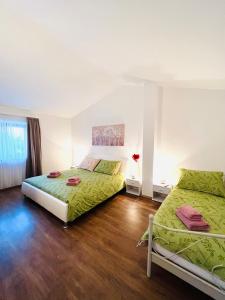 sypialnia z 2 łóżkami z zieloną pościelą i drewnianą podłogą w obiekcie Funcic Apartments 1 app w Puli