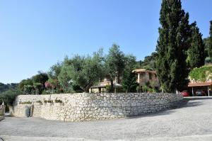 a stone wall with trees and a house behind it at Villa Belvedere - Sea view apts near Banana beach in Vasilikos