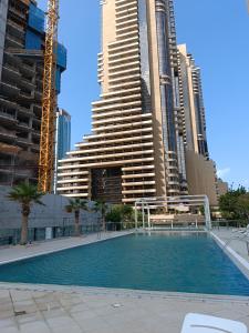 a swimming pool in front of some tall buildings at Vacay Lettings - 1 Bed at Iris Blue, Dubai Marina in Dubai
