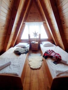 a attic bedroom with two beds and a window at Domek Poniwiec Mała Czantoria in Ustroń