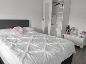 a white bed with a pink pillow on top of it at Apartment am See - Borken, Hessen in Borken