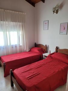 2 camas en una habitación con sábanas rojas y una ventana en Casa frente al mar Monte Hermoso en Monte Hermoso
