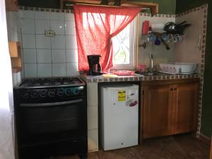 cocina con fogones, nevera y ventana en Axelmaria en Bajo Boquete