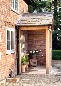 a wooden shed with a roof on a brick house at The Stable, Yew Tree Farm Holidays, Tattenhall, Chester in Chester