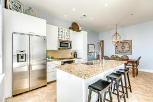 a kitchen with white cabinets and a large island with bar stools at Diamond Beach Resort Seawall Stunner in Galveston