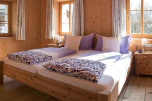 two beds in a room with wooden walls and windows at Marhof Pustertal in Anras