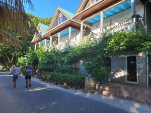 two people walking down a street in front of a building at Moonlight Beach Villa in La Digue