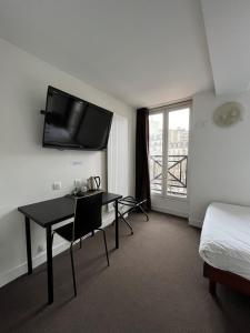 a hotel room with a desk and a tv on the wall at Hotel de la Tour in Paris