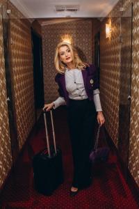 une femme debout dans un couloir avec ses bagages dans l'établissement Hotel Novera, à Timişoara