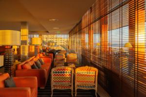uma sala de espera com cadeiras laranja e janelas em Algarve Casino Hotel em Portimão