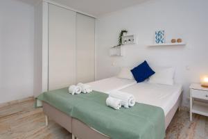 a white bedroom with two beds with towels on them at Duas Palmeiras by LovelyStay in Albufeira