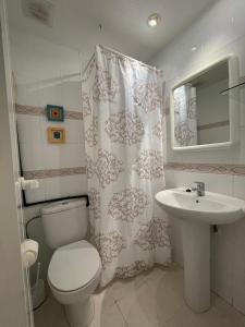 a bathroom with a toilet a sink and a shower curtain at APCOSTAS Cala Gonzalez in Alcossebre +8 photos