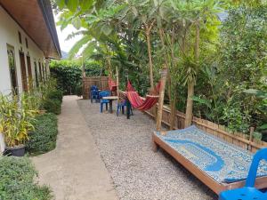 NongkhiawにあるMeexok guesthouseの庭園内のパティオ(ハンモック、椅子付)