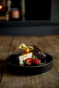 a black plate of food with fruit on a table at The George Hotel in Kirton in Lindsey