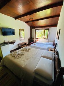 a large bedroom with two beds and a tv at Hotel Casa Alpina in Núcleo Mauá