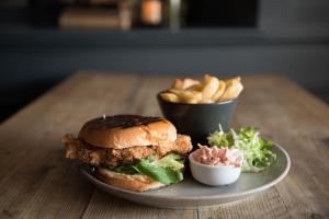 a plate with a chicken sandwich and fries on a table at The George Hotel in Kirton in Lindsey