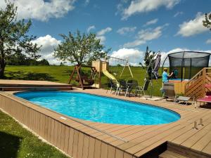 a swimming pool with a wooden deck and a playground at Ferienhof Schrädobler in Kößlarn