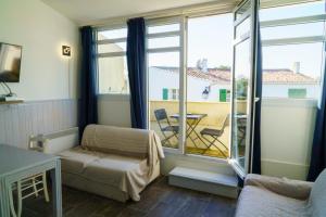a bedroom with a bed and a balcony with a table at Appartement 91 Palais des Gouverneurs in Saint-Martin-de-Ré