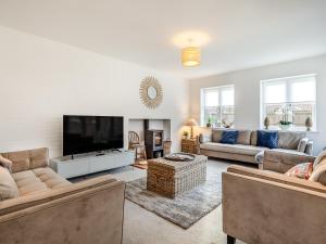 uma sala de estar com sofás e uma televisão de ecrã plano em Schaels Retreat em Binham