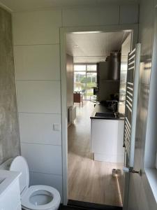 a bathroom with a white toilet and a kitchen at Luxus Chalet Waterfront in Lathum
