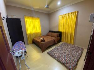 a bedroom with a bed and a chair and yellow curtains at Homestay Kimanis Papar in Kimanis