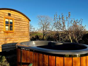 un bain à remous en face d'un bâtiment en bois dans l'établissement Robins Retreat - orchard with hot tub - see extras, à Alfriston