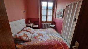 Un dormitorio con una cama con edredón y una ventana. en T2 avec terrasse vue Hautacam dans villa historique "Victoria", en Argelès-Gazost