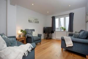 a living room with two blue chairs and a tv at Shell Cottage in Sidmouth