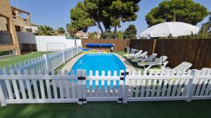a white fence around a pool with chairs and an umbrella at Villa Paraíso in Torremolinos