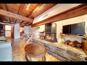 un soggiorno con camino in pietra con tv di CASA PINS de Alma de Nieve a Baqueira-Beret