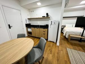 a room with a table and a bed and a refrigerator at Studios Cityhome Maxplaza Canoas in Canoas