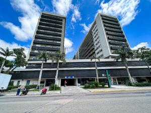 a tall building with palm trees in front of it at Studios Cityhome Maxplaza Canoas in Canoas