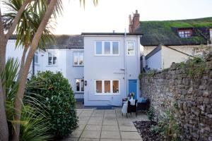 a white house with a blue door and a stone wall at Shell Cottage in Sidmouth