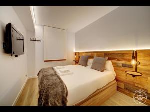 1 dormitorio con 1 cama y TV en la pared en MANAUD de Alma de Nieve, en Baqueira Beret