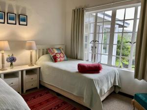 1 dormitorio con 2 camas y ventana en Woodcroft, en Lidgetton