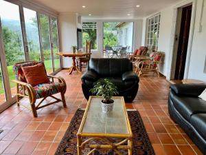 a living room with black leather furniture and a table at Woodcroft in Lidgetton +20 photos