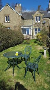 a table and two chairs in the yard of a house at Simonside Cottage nr Rothbury in Morpeth