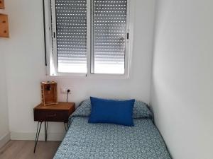 a bedroom with a blue pillow and a window at Ático centro Huelva con parking in Huelva