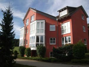 a red building with white windows and a tree at Harztraum 5 in Braunlage