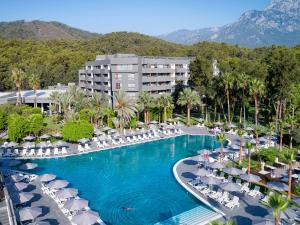 uma piscina com cadeiras e guarda-sóis num resort em Movenpick Resort Antalya Tekirova em Tekirova