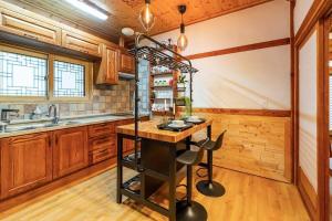 a kitchen with wooden cabinets and a island with stools at Elon Hanok Pension in Yeosu