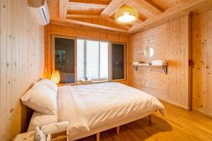 a bedroom with a large bed in a room with wooden walls at Elon Hanok Pension in Yeosu