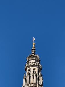 a tower with a cross on top of it at Au pied du Beffroy in Arras